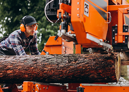  man from tree company uses stump grinding machine near Walled Lake, MI